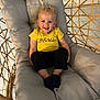 Paul participe au concours pour gagner de l'argent avec cette photo : black_pants, child, curly_hair, cushion, cute, feet, floor_tiles, furniture, happy, indoor, person, portrait, relaxed, seat, smiling, socks, toddler, wicker_chair, yellow_shirt, young