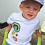 Paul a rejoint le concours — aidez-le/la à gagner de superbes lots ! boy, cap, cartoon_patches, casual, child, clothing, cute, green_chair, happy, hat, jeans, outdoor, person, plastic_chair, playful, portrait, sitting, smiling, white_tshirt, young