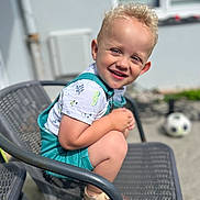 Paul a rejoint le concours — aidez-le/la à gagner de superbes lots ! blonde_hair, casual_clothing, chair, child, crouching, curly_hair, cute, daylight, happy, metal_chair, outdoor, playful, portrait, sandals, shorts, smiling, soccer_ball, summer, sunlight, toddler