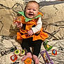 Aeva is registered to the contest to win money with this photo: baby, pumpkin_costume, orange, black_leggings, candy, halloween, smile, happy, sitting, couch, blanket, foot, hand, face, holiday, celebration, indoor, child, cute, festive