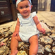 Athena joined the competition — help win amazing prizes! baby, child, infant, smiling, blue_clothing, headband, sitting, blanket, indoor, carpet, pacifier, furniture, face, cute, happy, person, portrait, baby_girl, skin, home