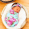 newborn, baby, sleeping, portrait, floral_blanket, headband, bow, basket, white_fur, swaddled, infant, face, closed_eyes, indoor, wooden_floor, nursery, peaceful, colorful, photography, closeup