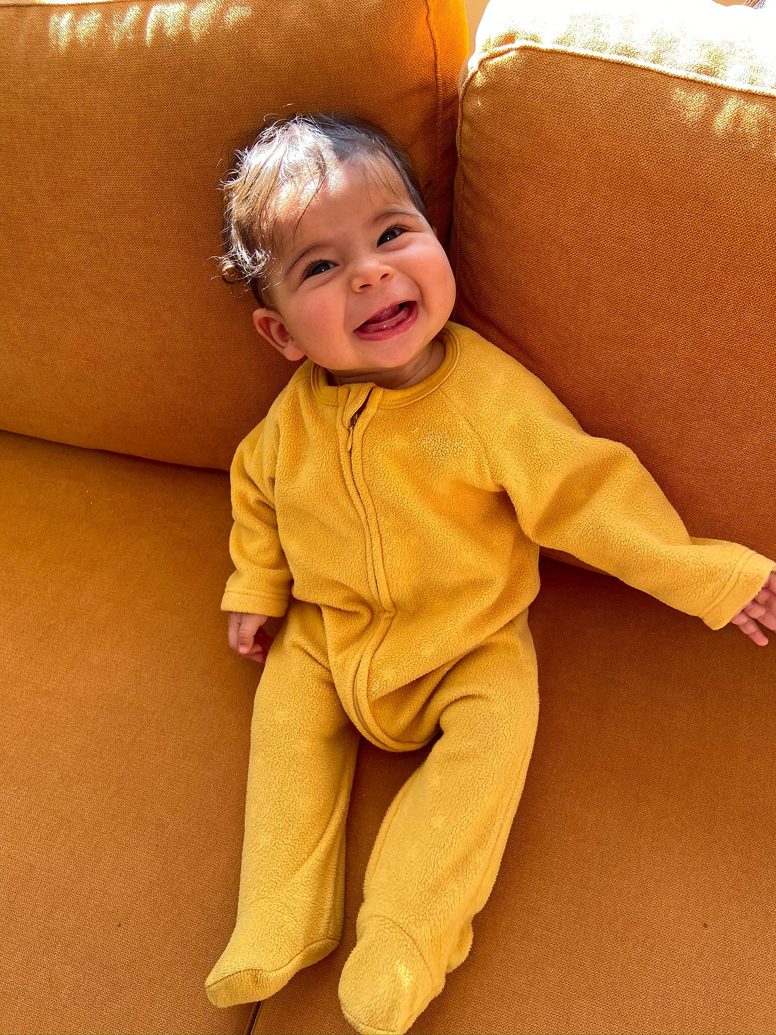Célina a rejoint le concours — aidez-le/la à gagner de superbes lots ! baby, baby_toddler_clothing, cheek, child, comfort, couch, eye, face, floor, flooring, foot, happy, hardwood, head, human_leg, person, sitting, sleeve, smile, toddler
