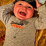 Lincoln joined the competition — help win amazing prizes! baby, child, smiling, laughing, bandana, headwear, grey_shirt, text_on_clothing, lying_down, happy, indoors, face, cute, infant, person, apparel, patterned, fabric, closeup, joyful