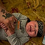 Lincoln is registered to the contest to win money with this photo: baby, infant, smiling, bandana, tattooed_hand, holding_hands, onesie, lying_down, blanket, patterned_blanket, happy, cute, human_hand, skin, portrait, indoor, child, person, closeup, toddler