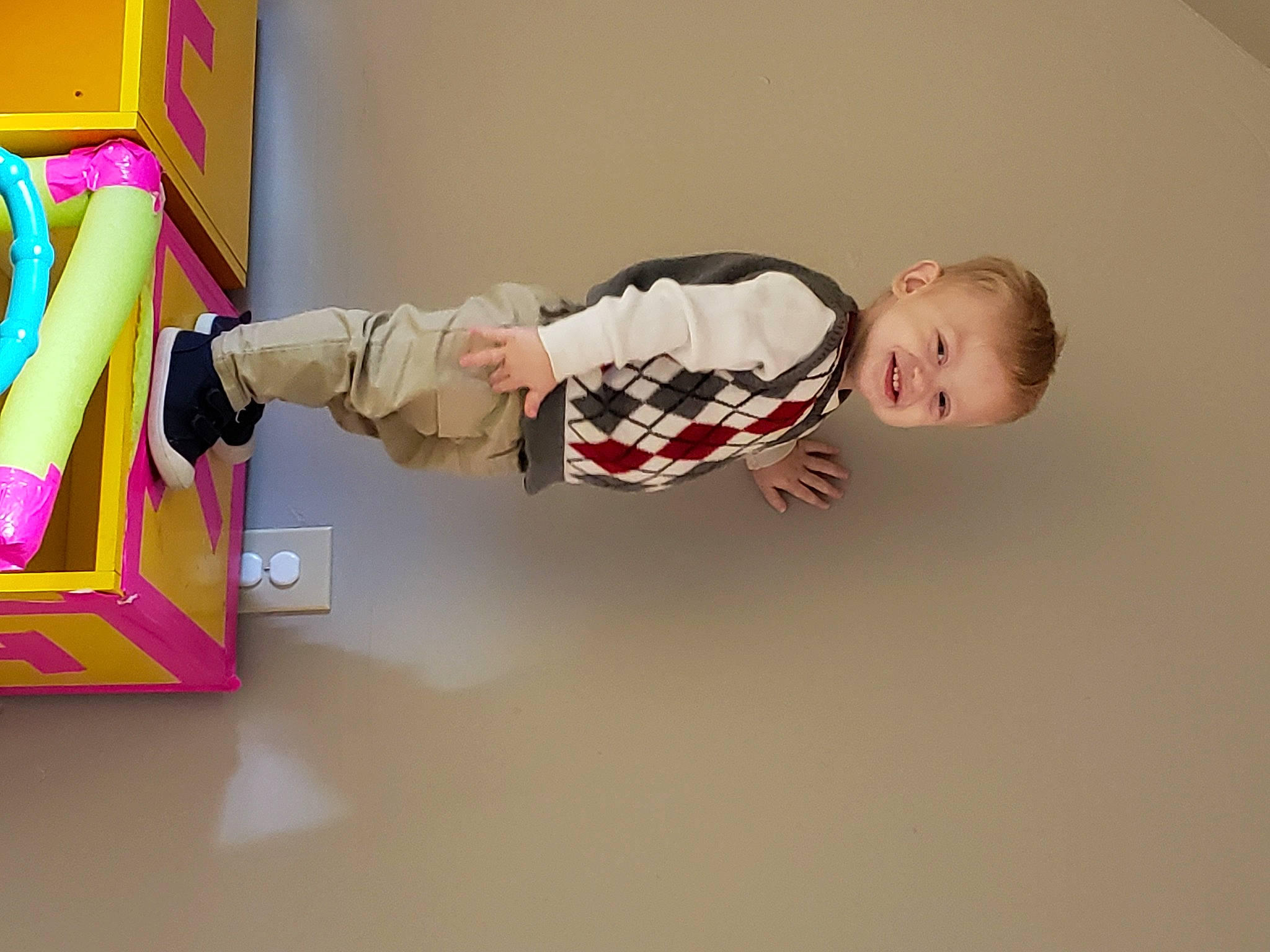 Jax is registered to the contest to win money with this photo: art, baby, baby_products, baby_toddler_clothing, baby_toys, cardboard, child, elbow, flooring, fun, hardwood, joy, magenta, paper_product, person, room, sleeve, sock, toddler, toy