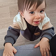 Timéo participe au concours pour gagner de l'argent avec cette photo : baby, candid, child, closeup, cozy, curious, cute, face, furniture, hands, holding, indoor, looking_up, person, smiling, sweater, texture, toddler, wooden_floor, young_child