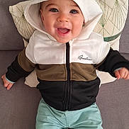 Timéo a rejoint le concours — aidez-le/la à gagner de superbes lots ! baby, child, hoodie, hood, smiling, happy, pants, couch, pillow, sitting, indoor, face, clothing, cute, infant, portrait, young_child, casual_wear, joyful, baby_girl_or_boy