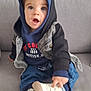 Timéo a rejoint le concours — aidez-le/la à gagner de superbes lots ! toddler, child, hoodie, denim_jacket, shoe, sneakers, couch, indoor, cute, pointing, expression, face, clothing, sitting, footwear, person, young_child, casual, blue, gray