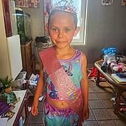 Laura a rejoint le concours — aidez-le/la à gagner de superbes lots ! birthday, celebration, child, decor, face, floor_tiles, flowers, furniture, girl, indoor, light, pajamas, person, plants, portrait, sash, smile, table, tiara, window