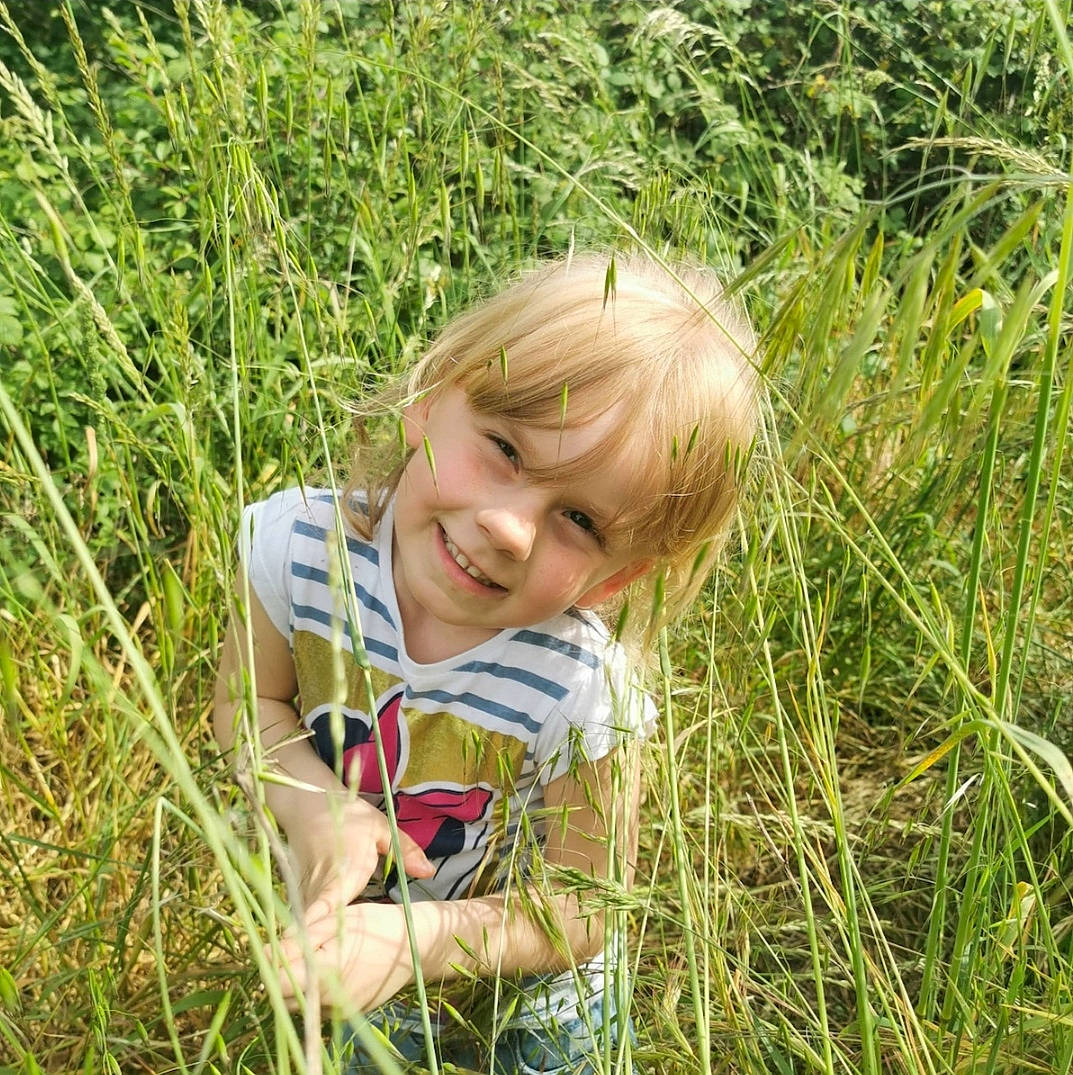 Ylana participe au concours pour gagner de l'argent avec cette photo : agriculture, child, ecoregion, field, grass, grass_family, grassland, groundcover, happy, joy, meadow, natural_landscape, pasture, people_in_nature, person, plant, prairie, sitting, smile, soil