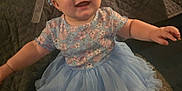 Kaylynn joined the competition — help win amazing prizes! baby, child, smile, flower_crown, blue_dress, tutu, happy, sitting, indoor, blanket, cute, portrait, infant, face, headwear, person, young_child, apparel, fabric, joyful