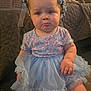 baby, child, pouty_face, flower_crown, blue_tutu, floral_shirt, sitting, indoor, carpet, blanket, cute, chubby_cheeks, person, toddler, happy, portrait, clothing, headwear, expression, home