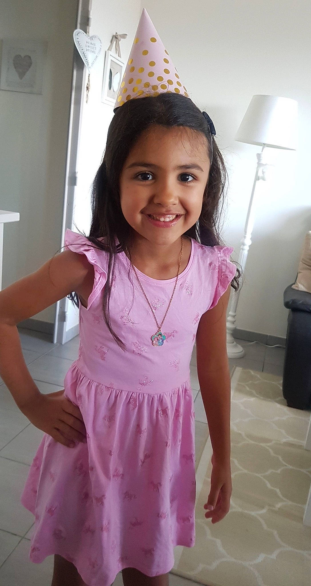 Stella participe au concours pour gagner de l'argent avec cette photo : clothing, day_dress, dress, face, facial_expression, fun, gesture, hair, hairstyle, happy, head, joy, neck, party_hat, person, pink, purple, skin, sleeve, smile