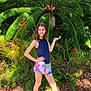 casual, child, daylight, feet, flora, girl, greenery, ground, happy, leaves, nature, outdoor, plant, posing, shoes, shorts, smile, sunlight, tank_top, young