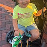 Samira is registered to the contest to win money with this photo: child, smiling, stroller, yellow_shirt, denim_shorts, sneakers, outdoor, daylight, brick_path, snack, happy, person, casual_clothing, footwear, green_grass, sunlight, playful, cute, park, summer