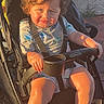 Jaziel is registered to the contest to win money with this photo: toddler, child, stroller, curly_hair, sunlight, outdoor, casual_clothing, shoes, seatbelt, expression, baby, summer, pavement, playful, person, young_child, graco, park, daylight, cute
