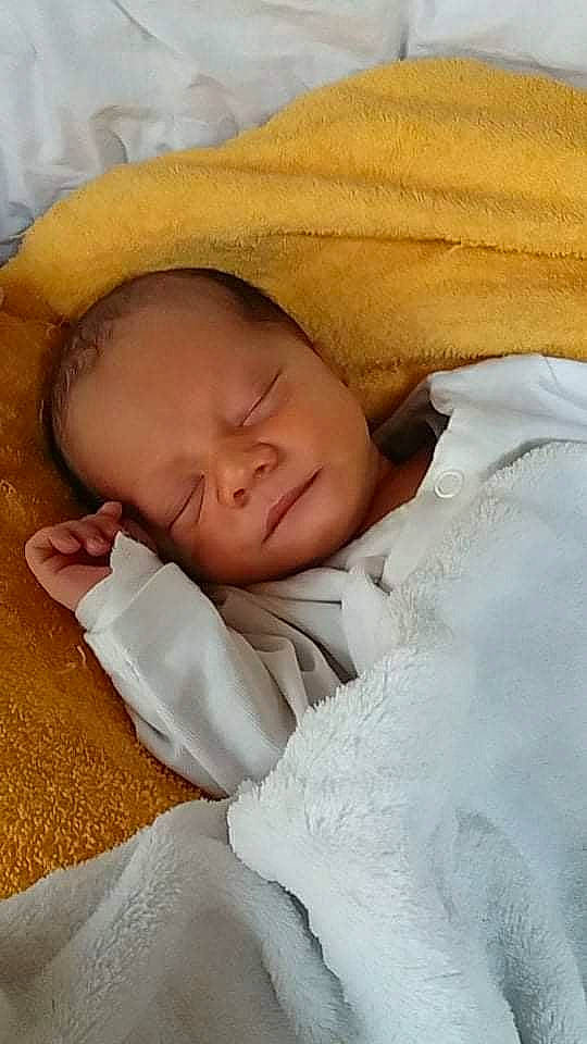 Ezéchiel a rejoint le concours — aidez-le/la à gagner de superbes lots ! baby, baby_products, baby_sleeping, baby_toddler_clothing, bed_sheet, bedding, bedtime, blanket, cheek, child, comfort, face, fur, happy, headgear, linens, nap, person, skin, sleep