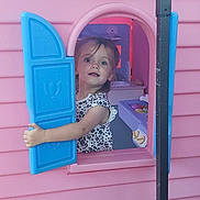 Maisie joined the competition — help win amazing prizes! backyard, blue, child, clothing, curious, daylight, dress, face, imagination, outdoor, person, pink, plastic, play, playhouse, shutter, smiling, toddler, toy, window