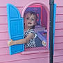 backyard, blue, child, clothing, curious, daylight, dress, face, imagination, outdoor, person, pink, plastic, play, playhouse, shutter, smiling, toddler, toy, window