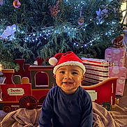 Kit joined the competition — help win amazing prizes! baby, child, santa_hat, christmas_tree, christmas_lights, gift, toy_train, blanket, holiday, festive, smiling, indoors, decorations, red, blue, cute, happy, seasonal, celebration, portrait