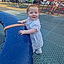 toddler, child, playground, outdoor, smiling, red_hair, white_dress, blue_play_structure, park, people, sunny, grass, trees, fence, casual_clothing, stroller, play_equipment, daytime, happy, person