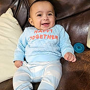 Rey joined the competition — help win amazing prizes! baby, smiling, infant, blue_clothing, striped_pants, socks, couch, leather, pillow, pacifier, bottle, happy, cute, child, indoors, portrait, seated, cozy, comfortable, home