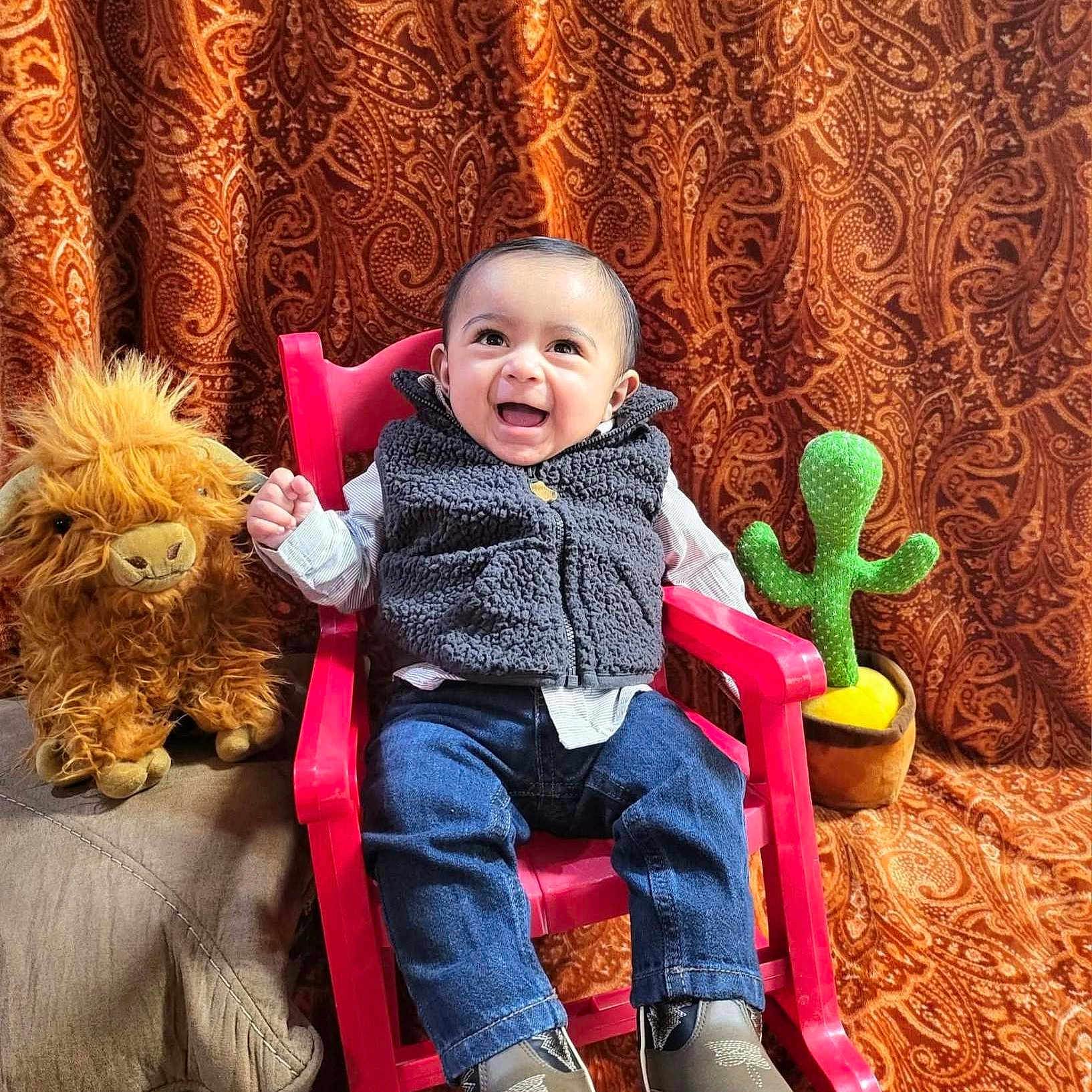 Rey joined the competition — help win amazing prizes! baby, background, cactus_plush, chair, child, clothing, cozy, cute, happy, indoor, jeans, lion_plush, patterned_curtain, plush_toy, portrait, rocking_chair, seated, shoes, smiling, vest