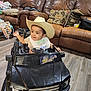 Rey joined the competition — help win amazing prizes! toddler, child, toy_car, cowboy_hat, indoor, leather_couch, bib, flooring, smiling, baby_bottle, pillow, backpack, wood_floor, happy, person, seat, clothing, furniture, play, home