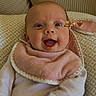 Jeanne participe au concours pour gagner de l'argent avec cette photo : baby, smiling, infant, bib, cushion, patterned, clothing, happy, face, head, person, indoor, cozy, skin, cheerful, cute, child, young, seated, comfort
