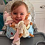 toddler, child, high_chair, smiling, plush_toy, baby, indoor, happy, cute, face, person, clothing, table, feeding_chair, toy, home, furniture, infant, baby_item, holding