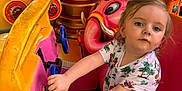 Maëlys a rejoint le concours — aidez-le/la à gagner de superbes lots ! child, toddler, amusement_ride, steering_wheel, colorful, pink, yellow, outdoor, daylight, trees, playful, cartoon_animal, flamingo, elephant, seatbelt, casual_clothing, short_sleeves, sneakers, portrait, curious