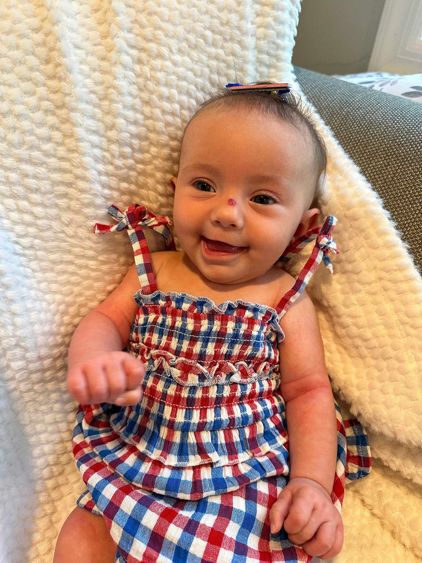 Sophia Grace joined the competition — help win amazing prizes! baby, smiling, dress, checkered_pattern, hair_clip, blanket, soft_texture, indoor, child, happy, cute, infant, sitting, hands, face, head, portrait, fabric, clothing, cozy