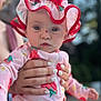 baby, child, infant, hat, red_bow, strawberry_pattern, pink_outfit, hand, adult_hand, nail_polish, outdoor, sunlight, portrait, cute, closeup, skin, face, eyes, expression, summer