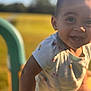 child, toddler, smiling, outdoor, playground, sunlight, happy, face, short_sleeve_shirt, colorful, grass, daylight, person, cute, young, nature, fun, joy, baby, park