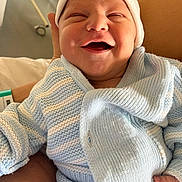 Emilio participe au concours pour gagner de l'argent avec cette photo : baby, newborn, smile, knitted_clothing, blue, white, hat, happy, infant, person, hand, cozy, cute, portrait, indoor, human, child, warm, wrapped, sitting