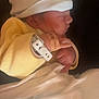 newborn, baby, sleeping, hat, yellow_clothing, blanket, hospital_band, infant, side_profile, peaceful, indoors, soft_light, cute, tiny_hands, wrapped, resting, close_up, child, person, warm