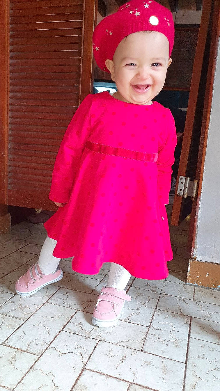Amira participe au concours pour gagner de l'argent avec cette photo : baby_toddler_clothing, clothing, door, dress, headwear, joy, leg, magenta, one_piece_garment, outerwear, pattern, person, photograph, pink, purple, red, sleeve, smile, snapshot, street_fashion
