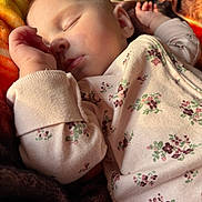 Serenity is registered to the contest to win money with this photo: baby, sleeping, infant, onesie, floral_pattern, blanket, cozy, peaceful, soft_light, close_up, child, rest, cute, skin, face, hand, nap, young, indoors, warm