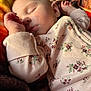 baby, sleeping, infant, onesie, floral_pattern, blanket, cozy, peaceful, soft_light, close_up, child, rest, cute, skin, face, hand, nap, young, indoors, warm