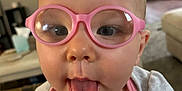 Serenity joined the competition — help win amazing prizes! baby, child, glasses, pink_glasses, tongue_out, close_up, face, cute, indoor, living_room, tshirt, playful, person, head, expression, home, infant, young_child, casual_clothing, funny_face