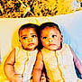 baby, babies, twin_babies, infant, yellow_outfit, bed, pillow, headboard, cute, child, portrait, indoor, sitting, holding_hands, matching_clothes, young_child, adorable, people, skin, expression