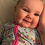 Millie joined the competition — help win amazing prizes! baby, child, face, smile, onesie, colorful_clothing, hand, tattoo, cheeks, portrait, closeup, infant, cute, happy, soft_lighting, indoor, person, head, eyes, skin