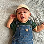 Mateo joined the competition — help win amazing prizes! baby, infant, child, overalls, denim, cap, hat, green_shirt, blanket, fuzzy_texture, lying_down, portrait, open_mouth, hand, ear, button, cute, soft_toy_top, smile_like_expression, face