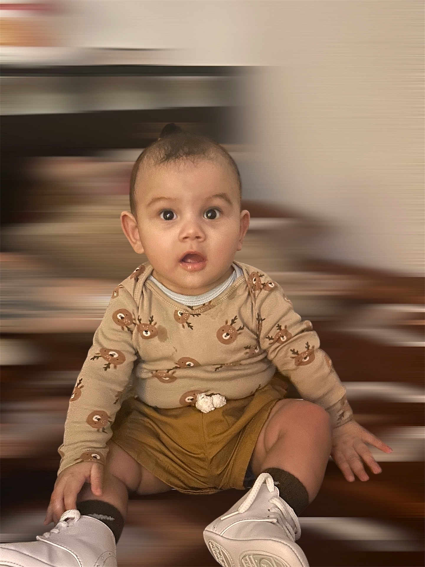 Mateo joined the competition — help win amazing prizes! baby, infant, child, sitting, surprised_expression, big_eyes, onesie, reindeer_print, shorts, sneakers, socks, hands, portrait, indoor, blurred_background, furniture, floor, cute, chubby_cheeks, photography