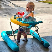 Ryker is registered to the contest to win money with this photo: toddler, walker, child, baby, standing, toy, colorful, curious, concrete_floor, outdoor, play, early_childhood, expression, footwear, socks, sunlight, driveway, plastic, infant, exploration