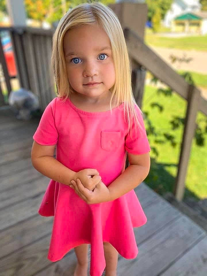 Ashlynne is registered to the contest to win money with this photo: baby_toddler_clothing, dress, eye, eyelash, face, grass, hair, happy, head, iris, lip, neck, one_piece_garment, person, pink, plant, shoulder, skin, sleeve, smile