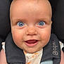 baby, child, face, blue_eyes, smiling, car_seat, harness, clothing, white_outfit, orange_prints, hair, close_up, portrait, infant, seatbelt, cute, happy, person, safety, straps