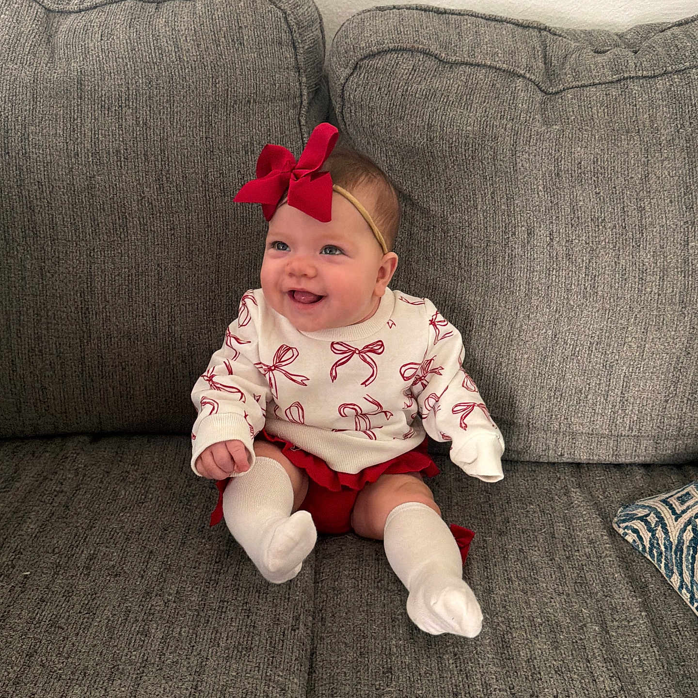 Wrenley joined the competition — help win amazing prizes! baby, child, couch, cozy, cute, fashion, gray_couch, happy, headband, home, indoor, infant, person, portrait, red_bow, red_skirt, sitting, smile, white_socks, white_sweater