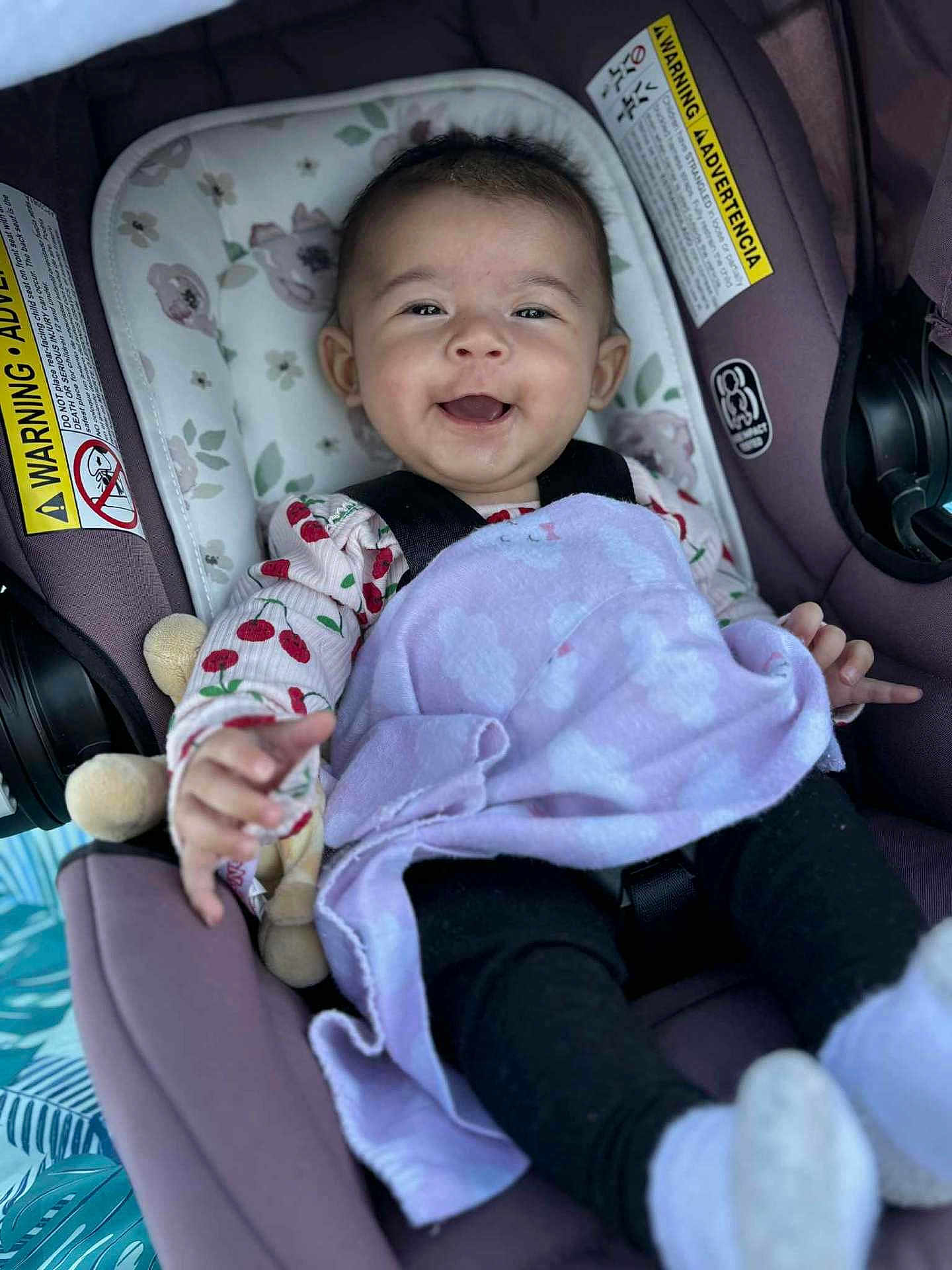 Ehlani joined the competition — help win amazing prizes! baby, car_seat, blanket, smiling, happy, child, infant, purple, clothing, face, cute, sitting, toy, pattern, black_pants, soft, indoor, comfort, young, portrait